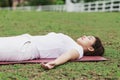 Beautiful Attractive Asian woman practice yoga Dead Body pose or Savasana pose lying on yoga mat with green grass for yoga Meditat Royalty Free Stock Photo