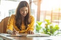 Beautiful Attractive Asian woman reading book and holding pencil thinking and writing data or business planning in paper Royalty Free Stock Photo