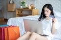 Beautiful Attractive Asian young woman lying on bed and using computer laptop for using social media and shopping online Royalty Free Stock Photo