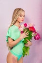 Beautiful attractive blonde young woman with african braids with tulips on pink background Royalty Free Stock Photo
