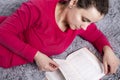 Beautiful attractive brunette girl is reading book on cozy sofa. Hobby reading books at home Royalty Free Stock Photo