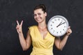 Beautiful attractive girl with a clock. A young woman is holding a round watch. Time concept