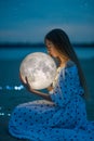 Beautiful attractive girl on a night beach with sand and stars hugs the moon, Artistic Photography Royalty Free Stock Photo