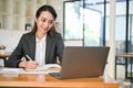 Asian female secretary or assistant writing or taking notes in her notebook while working Royalty Free Stock Photo