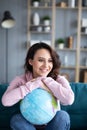 Beautiful attractive woman on couch holding globe and dreaming vacation