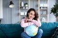 Beautiful attractive woman on couch holding globe and dreaming vacation Royalty Free Stock Photo