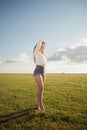 Beautiful and attractive woman with legs on grass shoe less watching the sun with her hand above her eyes