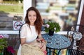 Beautiful attractive woman sit in a cafe and waiting for beverage. Coffee break. Caucasian girl enjoys a bright summer lifestyle Royalty Free Stock Photo