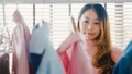 Beautiful attractive young Asia lady choosing her fashion outfit clothes in closet at house or store. Girl think what to wear Royalty Free Stock Photo