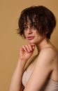 Beautiful attractive young European woman with wet short hair and perfect nude make-up, clean fresh healthy skin, wearing a beige Royalty Free Stock Photo