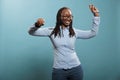 Beautiful attractive young lady dancing and vibing to funky disco music playlist on blue background. Royalty Free Stock Photo