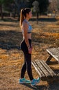 Beautiful attractive young toned runner, dressed in tights and a top, with long hair tied in a ponytail, stretching her calves