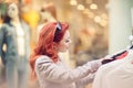Beautiful, attractive young woman with red hair relaxing in town, shopping, looking at store offers Royalty Free Stock Photo