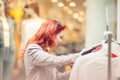 Beautiful, attractive young woman with red hair relaxing in town, shopping, looking at store offers Royalty Free Stock Photo