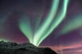 Beautiful Aurora Borealis green lights over a snowy mountain in Kvaloya, Arctic region, Norway