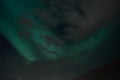 Beautiful aurora borealis on the night sky behind cloud cover