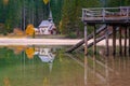 Beautiful autumn alpine landscape, spectacular old wooden pier and small church on Braies lake, Dolomites, Italy Royalty Free Stock Photo