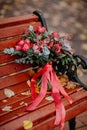 Beautiful autumn bouquet with red flowers and succulents on a bench outside
