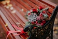 Beautiful autumn bouquet with red flowers and succulents on a bench outside