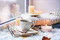 Beautiful autumn composition with burning candles and cup of tea on window sill Royalty Free Stock Photo