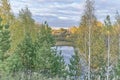 Beautiful autumn countryside landscape with pine trees, birches, pond and colorful cloudy sky Royalty Free Stock Photo