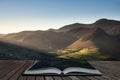 Beautiful Autumn Fall landscape image of sun beams lighting up small area of mountain side in Lake District coming out of pages of Royalty Free Stock Photo