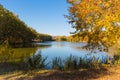 Beautiful autumn landscape. Blue sky, lake and yellow-green trees in the park Royalty Free Stock Photo