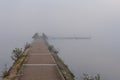 Beautiful autumn landscape with a bridge, stone pier, water, and mist Royalty Free Stock Photo