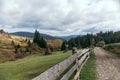 Beautiful autumn landscape of the Carpathian village in the mountains and a path along the fence. haystacks and coniferous forest Royalty Free Stock Photo