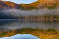 Beautiful autumn landscape with golden and copper colored trees and morning mist over the water Royalty Free Stock Photo