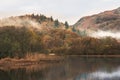 Beautiful Autumn landscape image of River Brathay in Lake District lookng towards Langdale Pikes with fog across river and vibrant Royalty Free Stock Photo