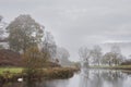 Beautiful Autumn landscape image of River Brathay in Lake District lookng towards Langdale Pikes with fog across river and vibrant Royalty Free Stock Photo