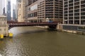 a beautiful autumn landscape with people walking and cars driving over the Monroe Street bridge over the Chicago River