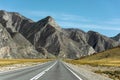 Beautiful autumn landscape. A straight road leading off into the distance. High mountains on the horizon Royalty Free Stock Photo