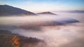 Beautiful Autumn mountain panorama. Morning thick fog cover valley aerial view. Fantastic fall sunrise Royalty Free Stock Photo