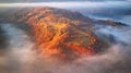 Beautiful Autumn mountain panorama. Morning thick fog cover valley aerial view. Red, Yellow, Orange trees on hillsides Royalty Free Stock Photo