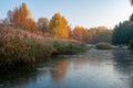 Beautiful autumn park at frosty morning. Yellowed trees reflected in the frozen water Royalty Free Stock Photo