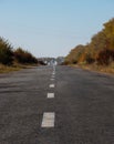 Beautiful autumn road. Autumn background. Country road made of old asphalt among beautiful trees with yellow and orange