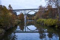 Beautiful autumn scenery of a bridge reflecting in the river surrounded by colorful trees Royalty Free Stock Photo