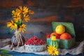 Beautiful autumn still life from different pumpkins in a wicker basket, yellow daisies in a clay ceramic brown ethnic vase on wood
