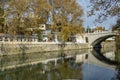 Beautiful autumn view of Sochi river with reflection of sky in water. River embankment with building and stone bridge.