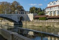 Beautiful autumn view of Sochi river with reflection of sky in water. River embankment with building and stone bridge.