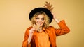 Beautiful autumn woman in black hat with autumnal foliage. Smiling girl in orange shirt and coat with autumn leaves