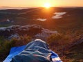 Beautiful awakening in a sleeping bag on rock ledge. Birds are singing and Sun at horizon.