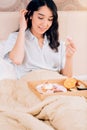 Beautiful awesome dark haired woman having tasty breakfast in bed at her cozy bedroom. Side view photo of young girl in blue Royalty Free Stock Photo