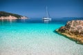Beautiful azure blue lagoon with sailing catamaran yacht boat at anchor. Pure white pebble beach, some rocks in the sea Royalty Free Stock Photo
