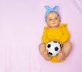 Beautiful baby girl lay with football ball in bed Royalty Free Stock Photo