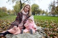 Beautiful baby girl with mother sitting on the plaid. Family outdoor Royalty Free Stock Photo