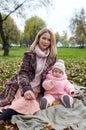 Beautiful baby girl with mother sitting on the plaid. Family outdoor Royalty Free Stock Photo