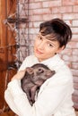 Beautiful smiling woman near a Christmas tree holding in hands black vietnamese piglet. Concept of the Chinese New Year Royalty Free Stock Photo